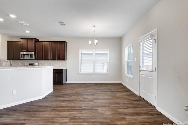 8116 Chasemont Ct, Converse, TX 78109 - kitchen with stainless steel microwave, backsplash, dark brown cabinets, a chandelier, and dark wood-style flooring