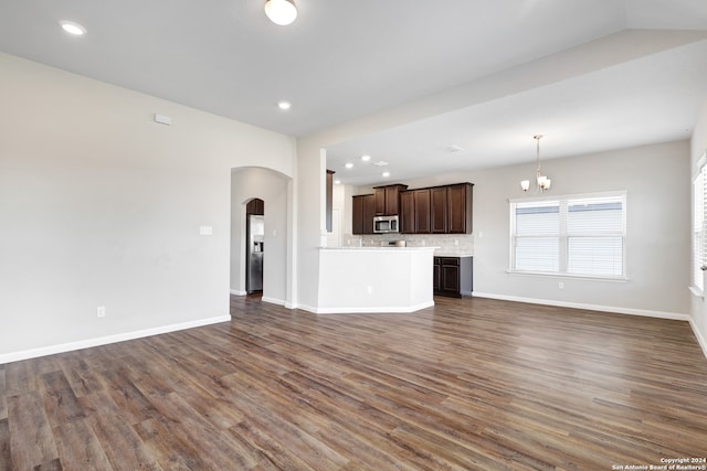 unfurnished living room with a notable chandelier and dark hardwood / wood-style flooring