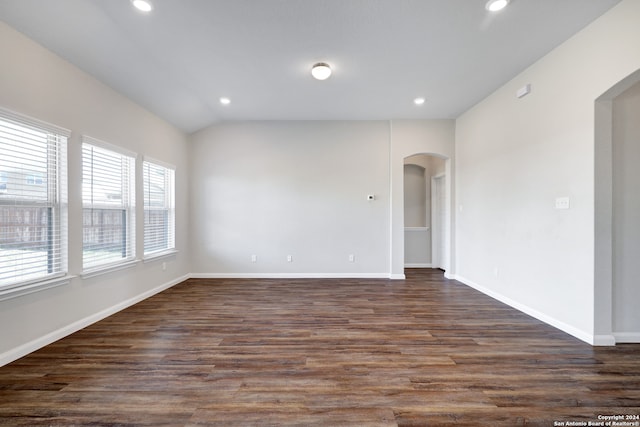 spare room featuring dark wood-type flooring and lofted ceiling