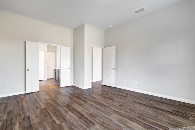 unfurnished bedroom featuring dark hardwood / wood-style flooring and a high ceiling