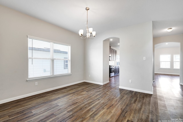 unfurnished room with dark wood-type flooring and an inviting chandelier