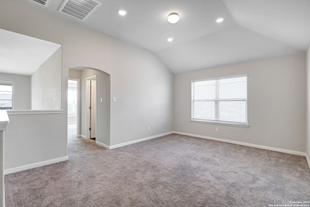 carpeted spare room with vaulted ceiling