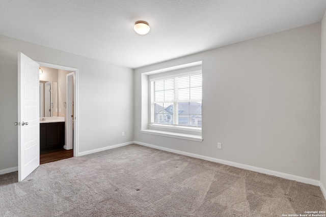 unfurnished bedroom with connected bathroom and carpet