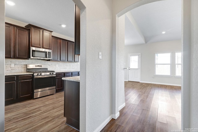 8116 Chasemont Ct, Converse, TX 78109 - kitchen with appliances with stainless steel finishes, backsplash, wood finished floors, dark brown cabinetry, and arched walkways