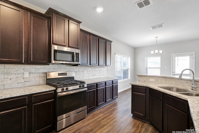 kitchen featuring dark brown cabinets, hanging light fixtures, appliances with stainless steel finishes, dark hardwood / wood-style floors, and sink