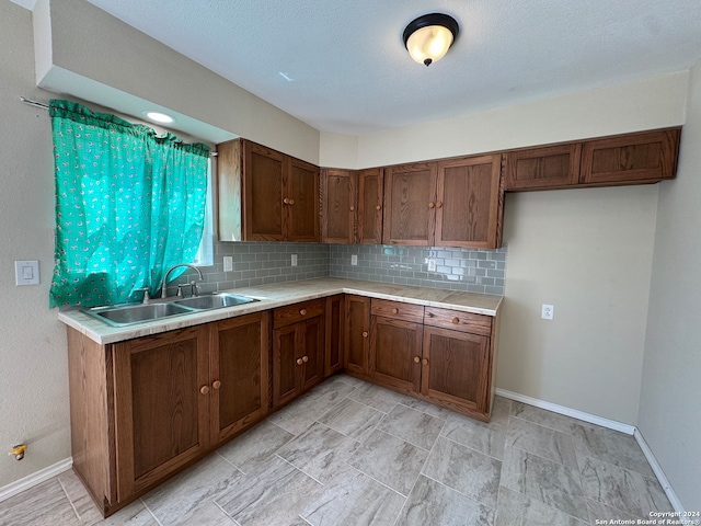 kitchen with tasteful backsplash, a textured ceiling, and sink