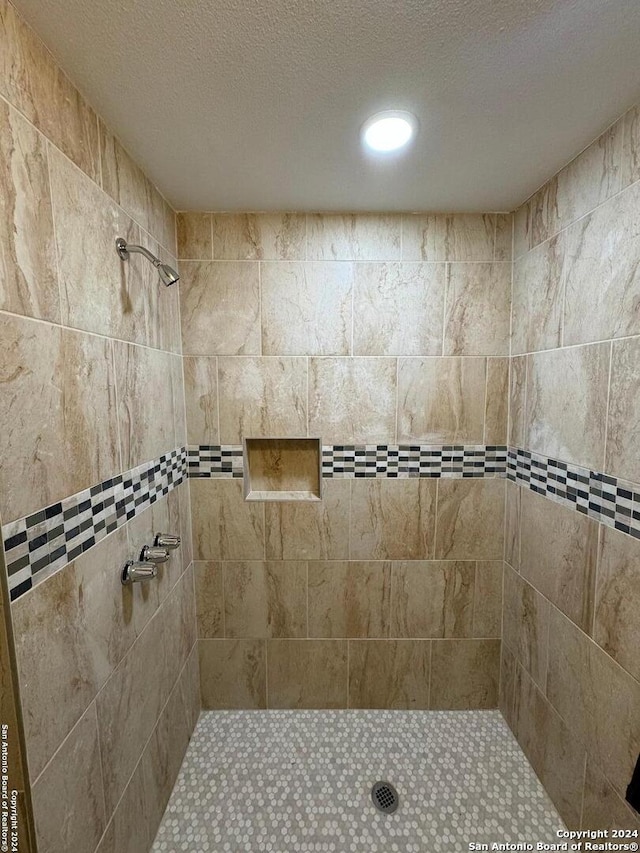 bathroom with a tile shower and a textured ceiling