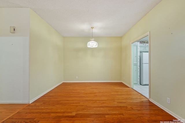 unfurnished room with a textured ceiling and wood-type flooring