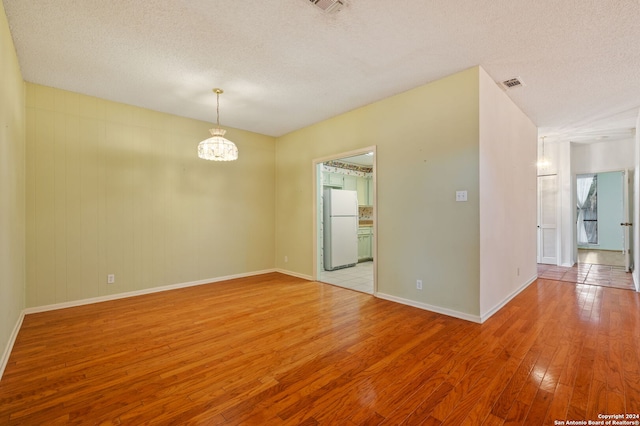 unfurnished room with a textured ceiling and light hardwood / wood-style flooring