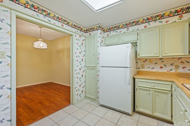 kitchen with light hardwood / wood-style flooring, hanging light fixtures, an inviting chandelier, white refrigerator, and a textured ceiling