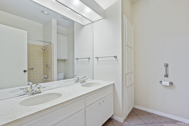 bathroom featuring a textured ceiling, toilet, tiled shower, vanity, and tile patterned flooring