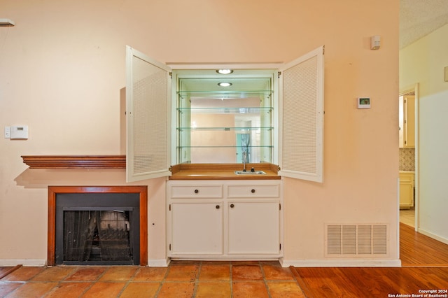 bar featuring tasteful backsplash, sink, light wood-type flooring, and white cabinets