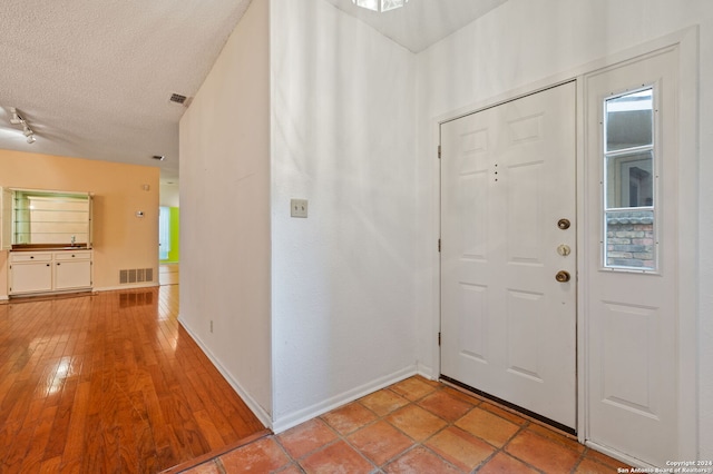 foyer entrance with light hardwood / wood-style flooring, a textured ceiling, and plenty of natural light