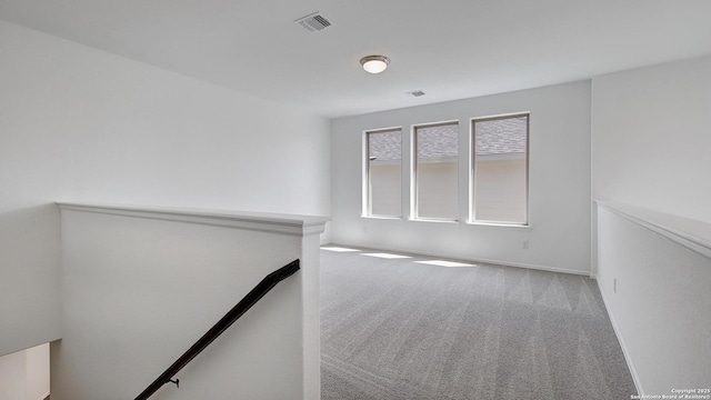 empty room featuring visible vents, baseboards, and carpet