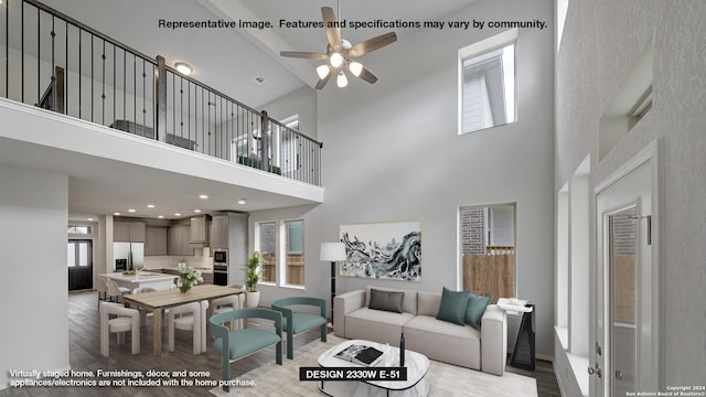 living room with a high ceiling, light hardwood / wood-style flooring, and ceiling fan