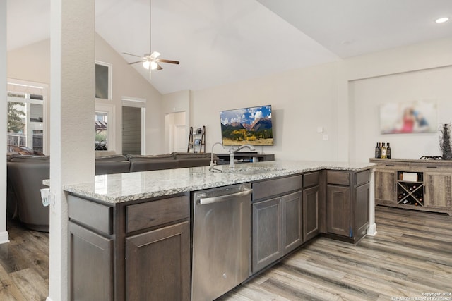 kitchen with light stone counters, hardwood / wood-style flooring, sink, and stainless steel dishwasher