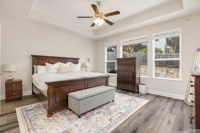 bedroom featuring dark hardwood / wood-style flooring, ceiling fan, and a raised ceiling