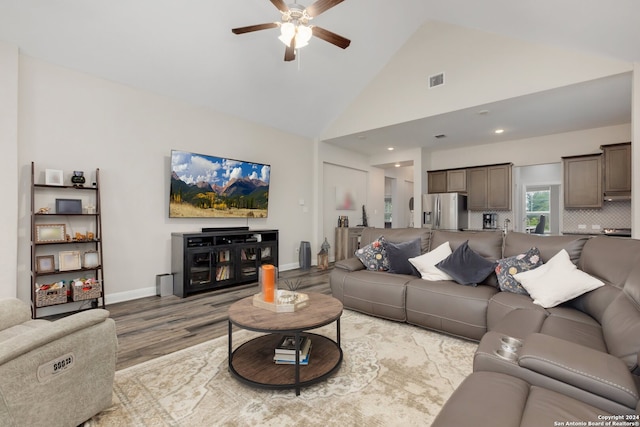 living room with hardwood / wood-style floors, high vaulted ceiling, and ceiling fan