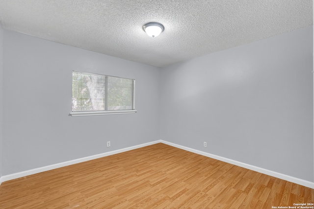 unfurnished room featuring a textured ceiling and light hardwood / wood-style flooring