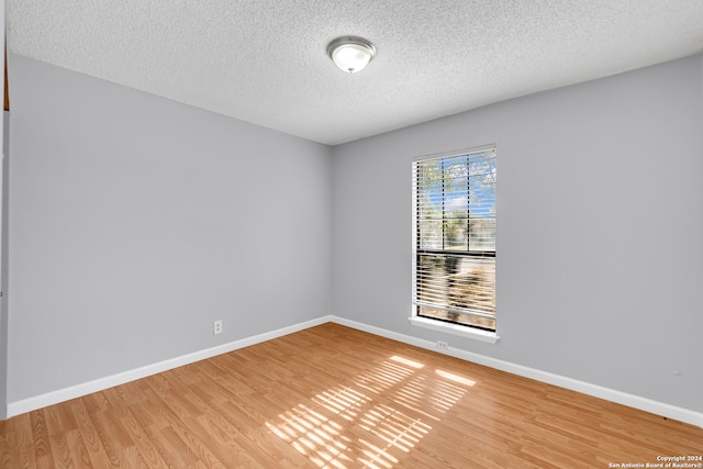 unfurnished room with wood-type flooring and a textured ceiling