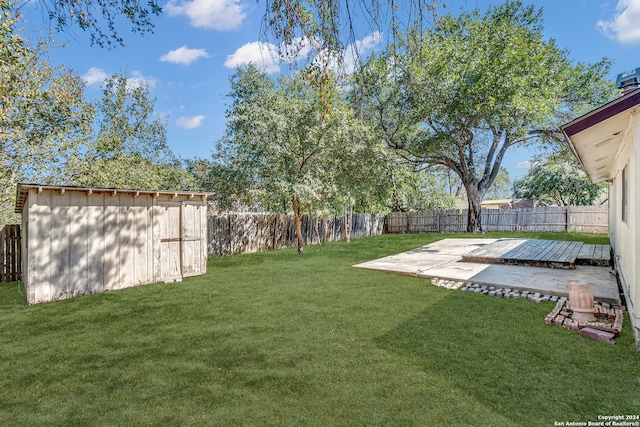 view of yard featuring a wooden deck, a patio area, and a shed