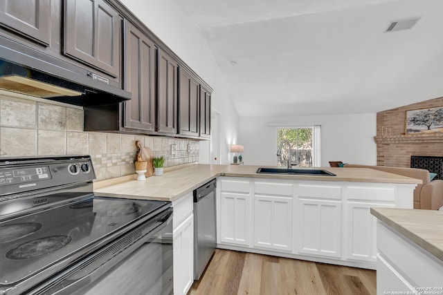 kitchen featuring kitchen peninsula, sink, vaulted ceiling, and black electric range