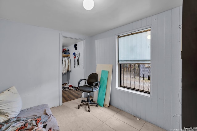 bedroom featuring light hardwood / wood-style flooring, a closet, and wood walls