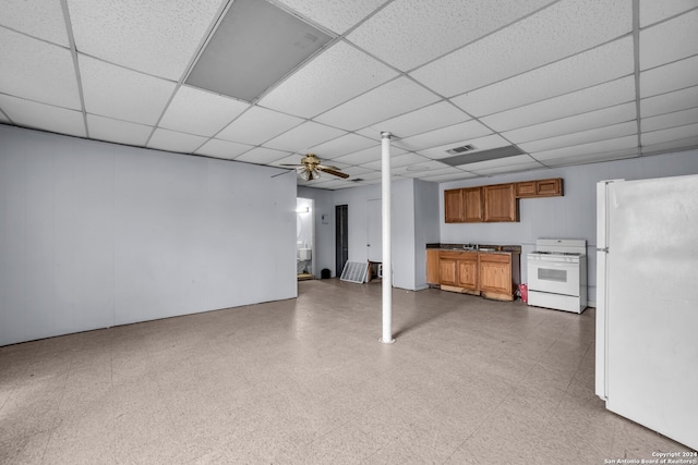 basement with a paneled ceiling, ceiling fan, and white refrigerator