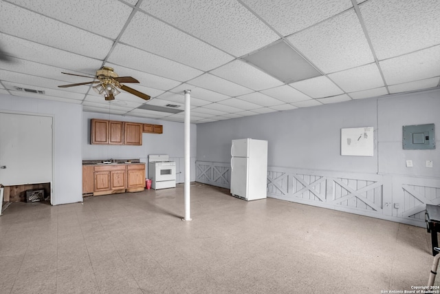 basement featuring a drop ceiling, white fridge, sink, and ceiling fan