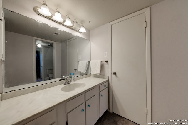 bathroom featuring vanity, a textured ceiling, and toilet