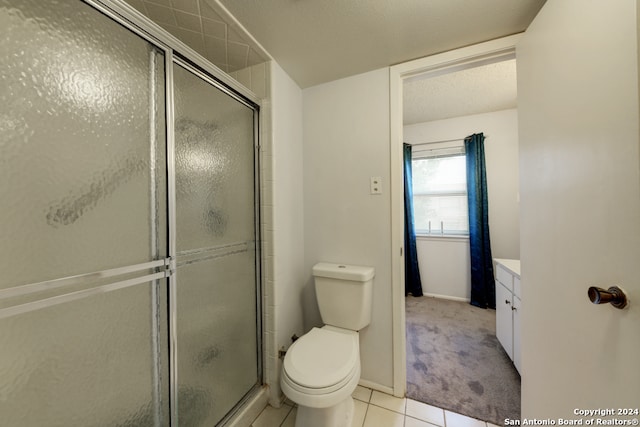 bathroom with vanity, toilet, tile patterned floors, and a shower with door