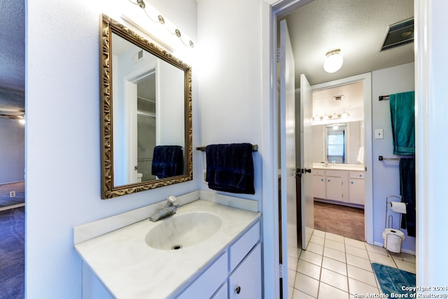 bathroom with vanity, a textured ceiling, and tile patterned flooring