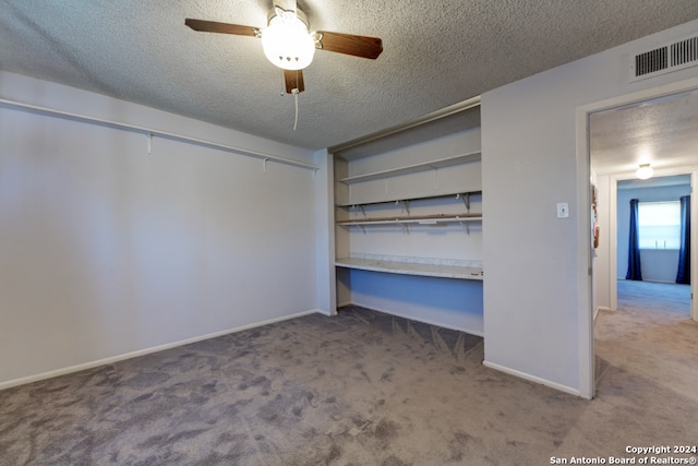 unfurnished bedroom featuring built in desk, carpet, a textured ceiling, and ceiling fan