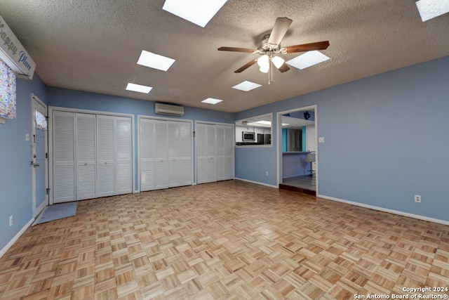 unfurnished room featuring a textured ceiling, a wall mounted air conditioner, light parquet flooring, and ceiling fan