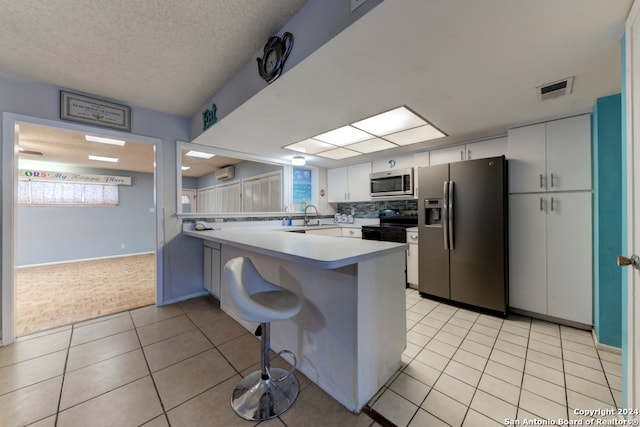 kitchen with a kitchen breakfast bar, white cabinets, kitchen peninsula, and stainless steel appliances