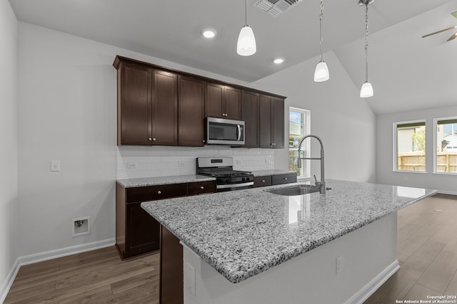 kitchen featuring appliances with stainless steel finishes, a kitchen island with sink, sink, and hanging light fixtures