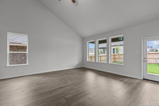 spare room with ceiling fan, a healthy amount of sunlight, dark wood-type flooring, and high vaulted ceiling