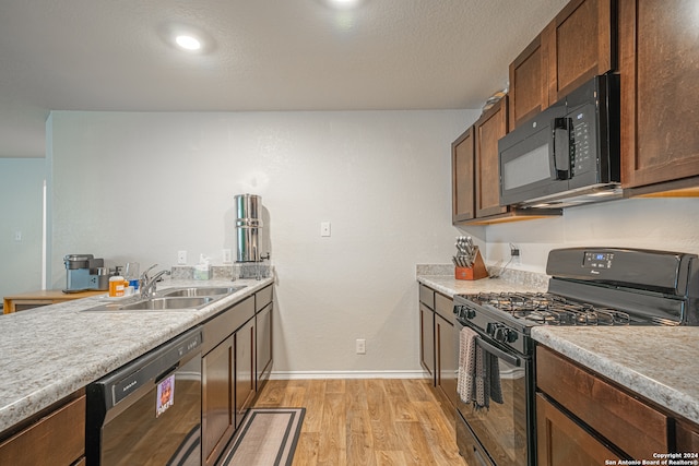 kitchen with light hardwood / wood-style floors, black appliances, and sink