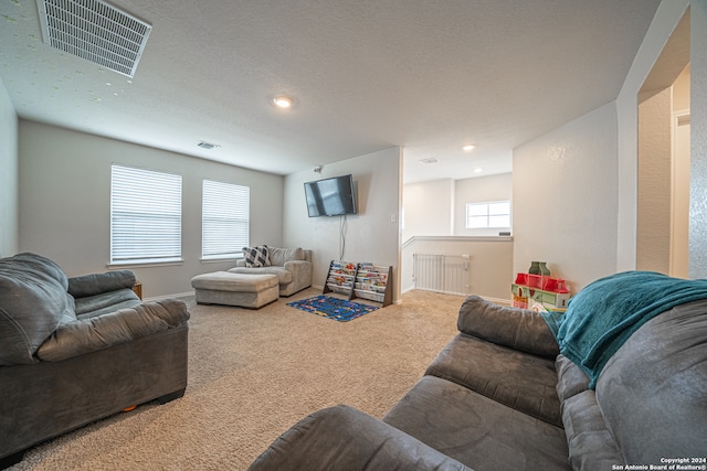 carpeted living room featuring a textured ceiling and radiator heating unit