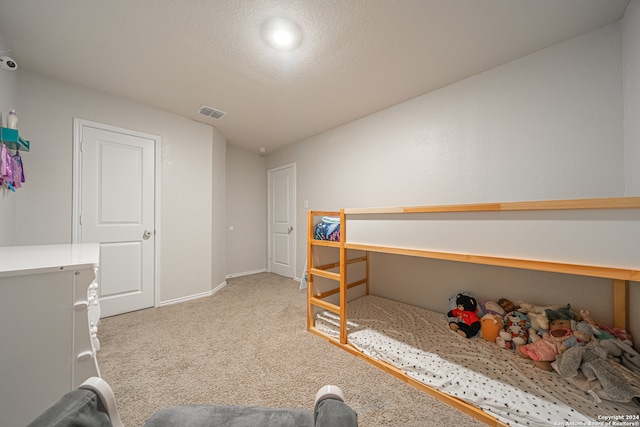 bedroom featuring light carpet and a textured ceiling