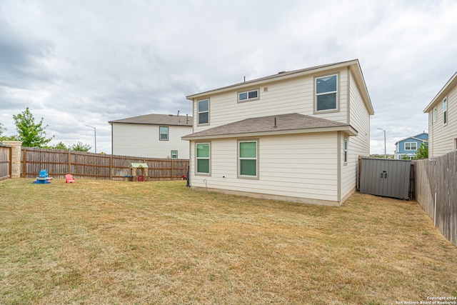 back of property with a storage shed and a lawn