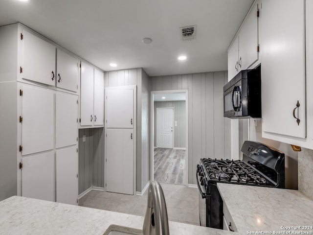 kitchen with white cabinetry, light hardwood / wood-style floors, and black appliances