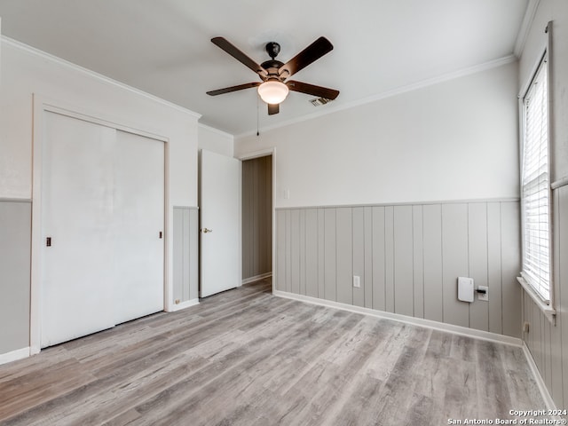 unfurnished bedroom featuring a closet, crown molding, light wood-type flooring, and ceiling fan