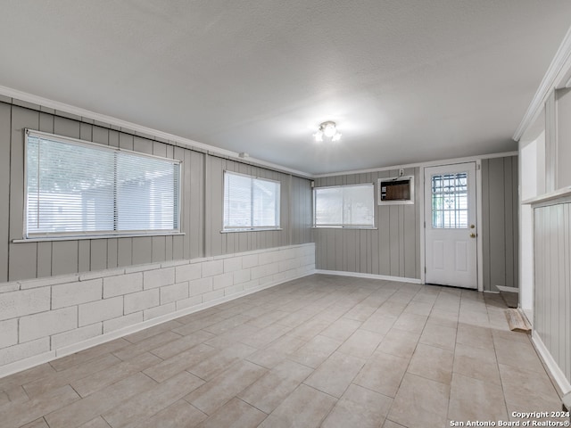 tiled spare room with crown molding, a wall unit AC, and a textured ceiling