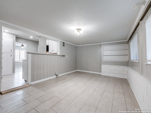 tiled spare room featuring crown molding and wooden walls