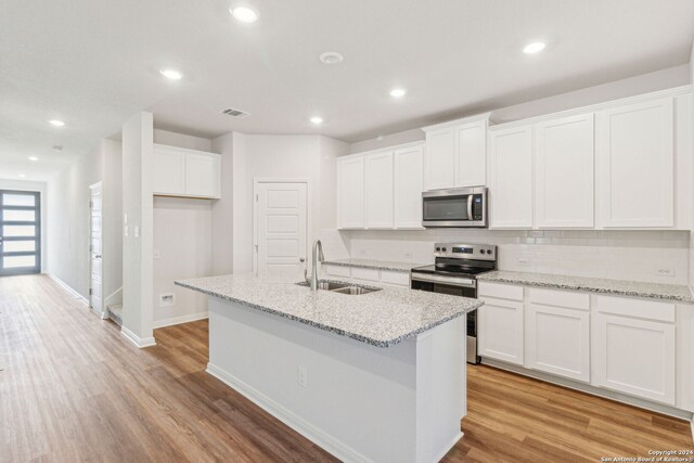 kitchen featuring white cabinets, sink, light hardwood / wood-style flooring, an island with sink, and stainless steel appliances