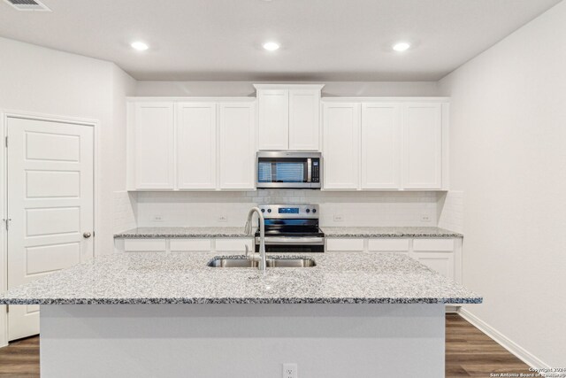 kitchen with dark hardwood / wood-style flooring, white cabinetry, an island with sink, and appliances with stainless steel finishes