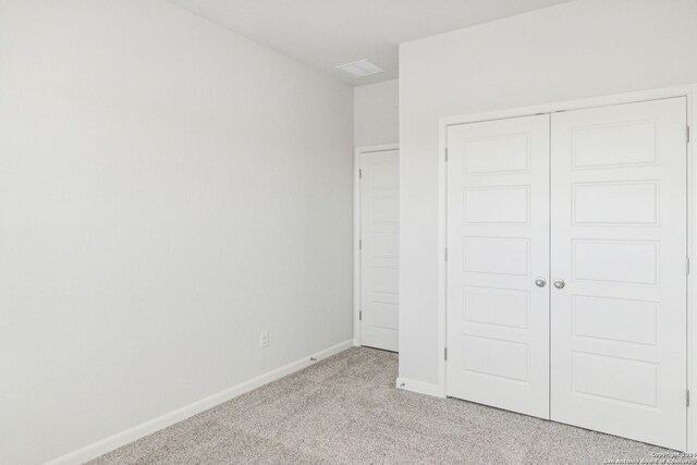 unfurnished bedroom with light carpet and a closet