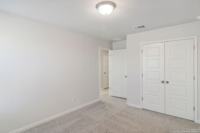 unfurnished bedroom featuring light colored carpet and a closet