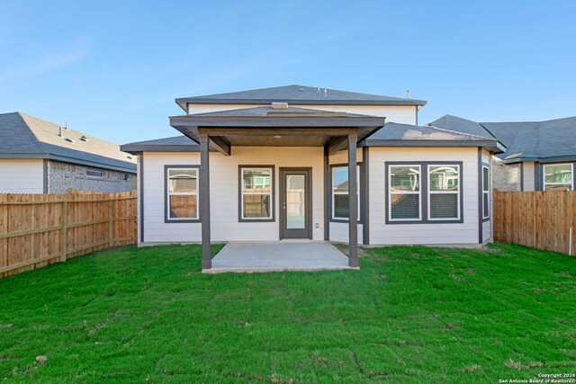 back of property with a yard and a patio